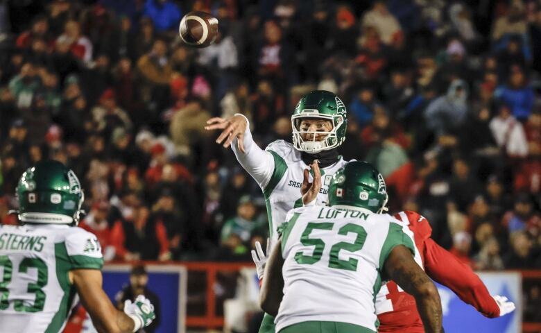 Roughriders quarterback Jake Dolegala throws the ball and other Roughriders are turned facing Dolegala