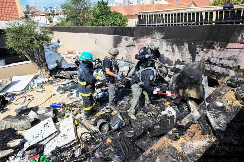 Firefighters look through the burned-out rubble of a house destroyed by rocket fire.