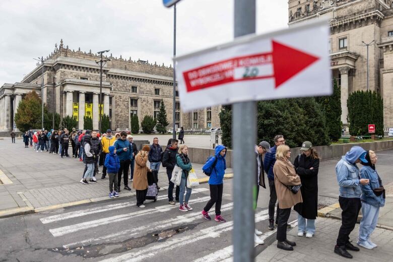 People are seen lining up on a sidewalk.