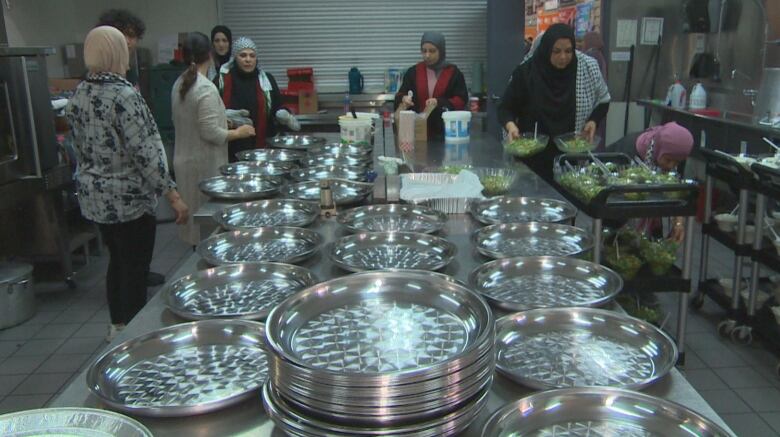 A group of women are pictured putting together plates of food.