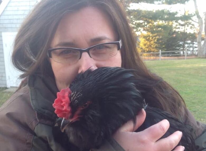 A woman hugs a rooster 