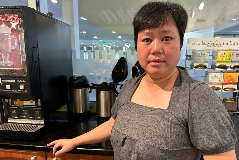 A woman stands behind the counter of a deli.