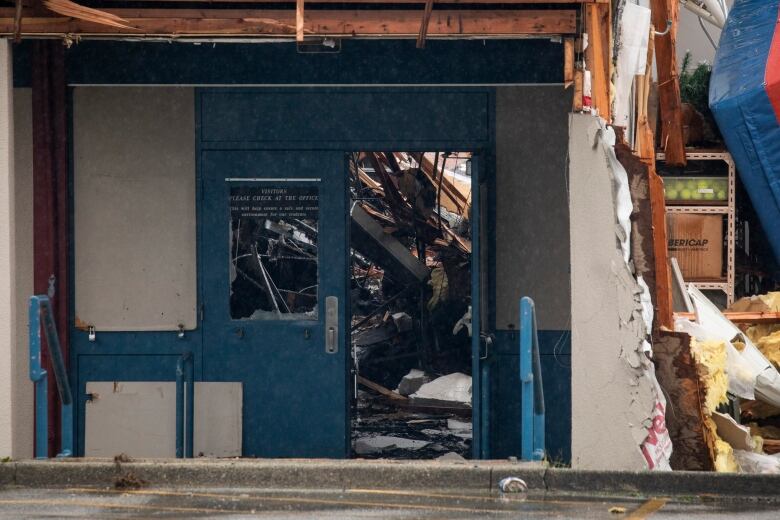 The entrance to a burned-out school, with 'visitors please check in at the office' still visible.