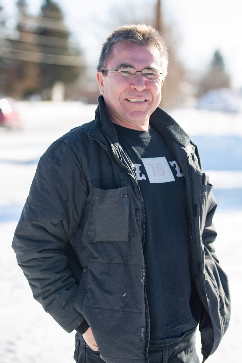 Les Wright, a man with white hair and glasses, wears a black jacket outside.