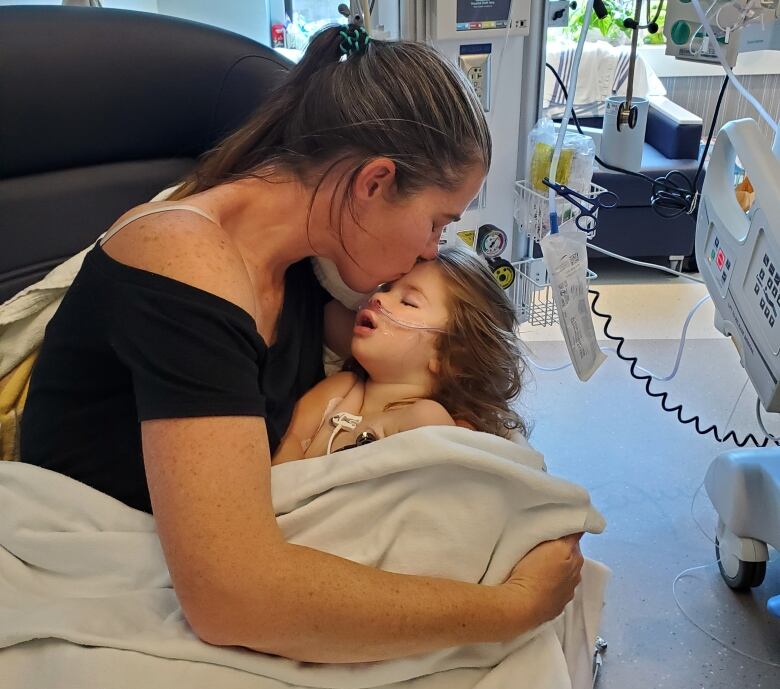 A woman kisses a toddler on the forehead.