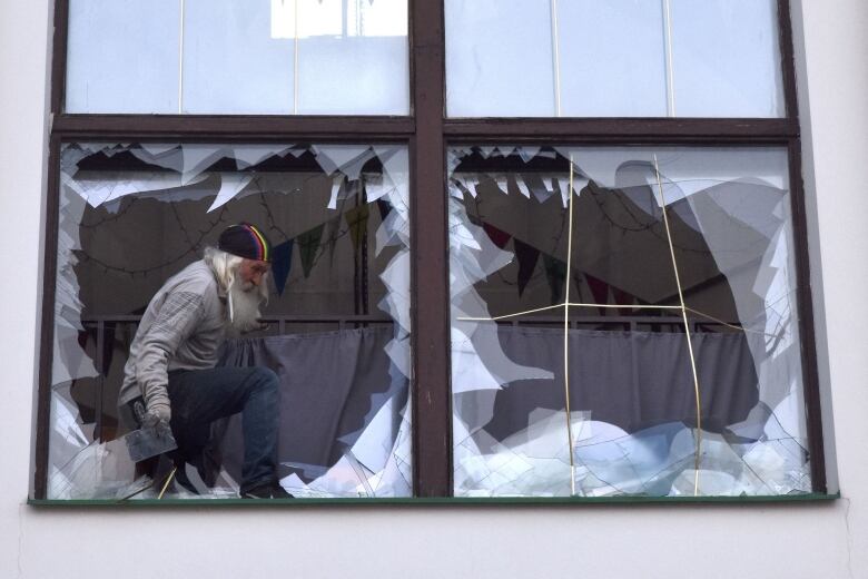 An Orthodox priest clears away broken glass at a Zaporizhzhia cathedral, which was damaged by missile strikes.