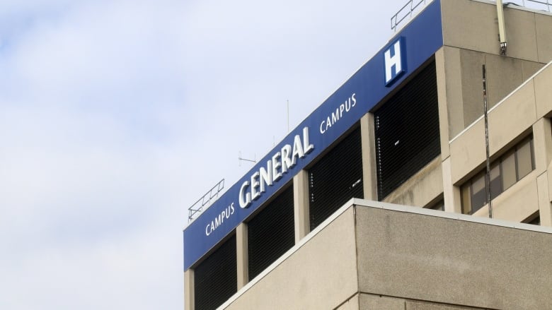 A blue-and-white hospital sign affixed to a grey concrete building.