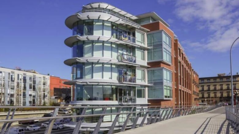 A shiny apartment building next to a bridge.