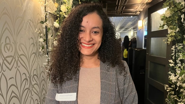 A woman wearing a name tag smiles. 