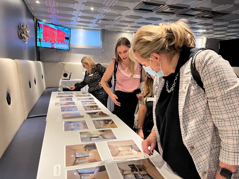 Women looking at photos of the inside of a furnished apartment. 