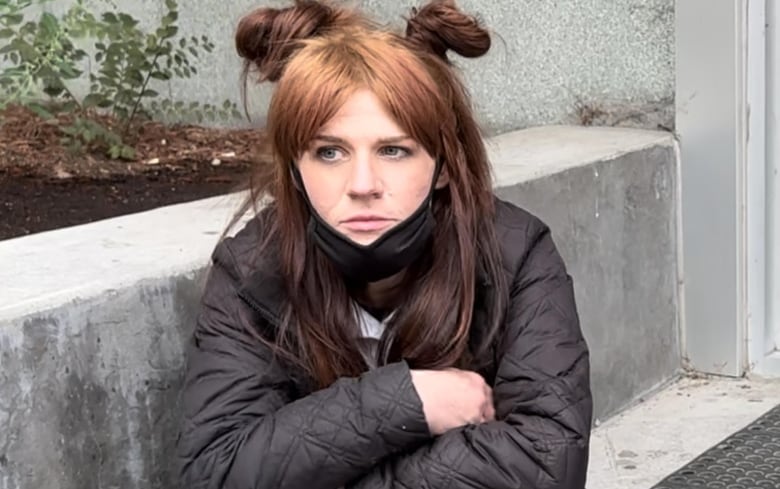 A woman sits on a set of concrete steps. 