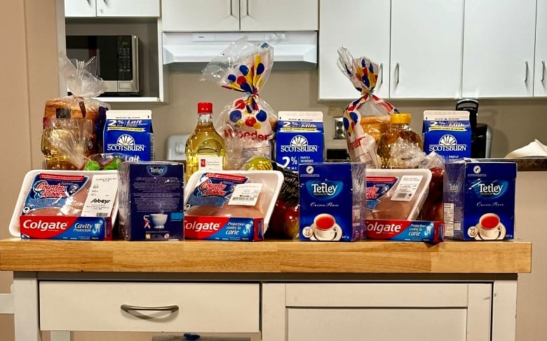 A display of groceries sits on a wooden shelf.