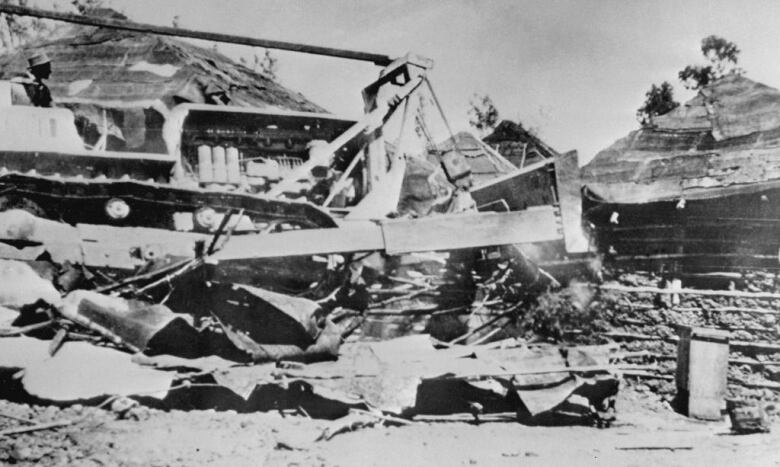 A bulldozer destroys homes in a village