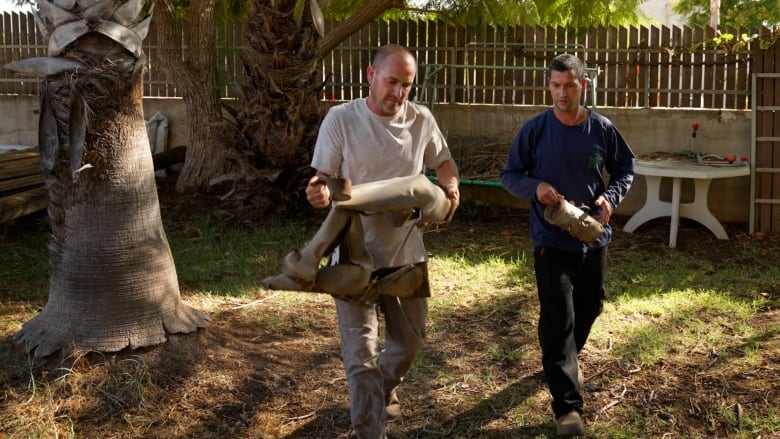 Two men carry a rocket.