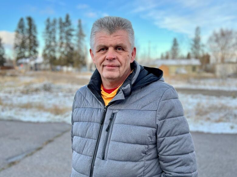 A man in a gray jacket stands outside. 