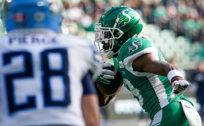 Saskatchewan Roughriders receiver Samuel Emilus is running with the ball and a Toronto Argonaut is facing him