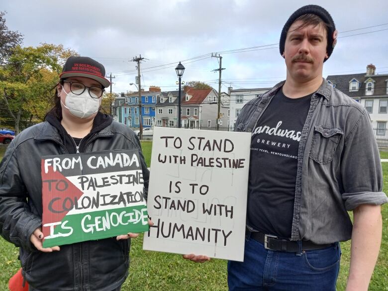 Two people hold signs in support of Palestine