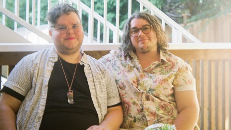 Two men smile while sitting on a patio.