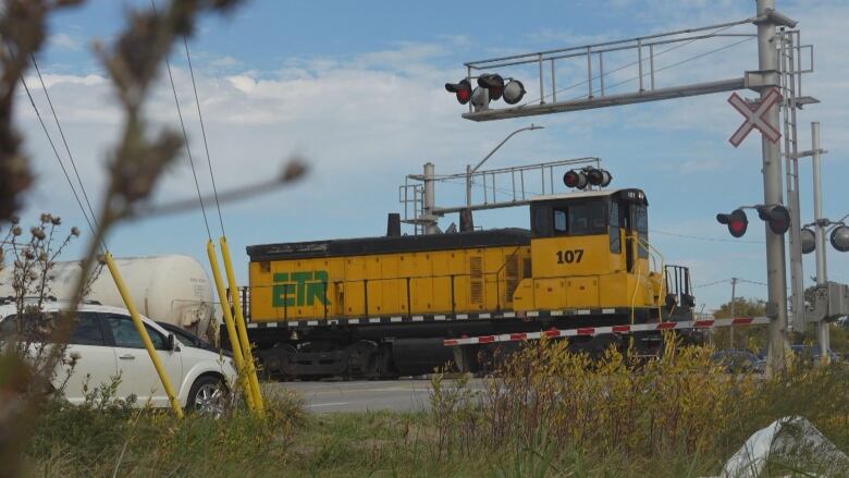 A yellow train moves through a railway corssing