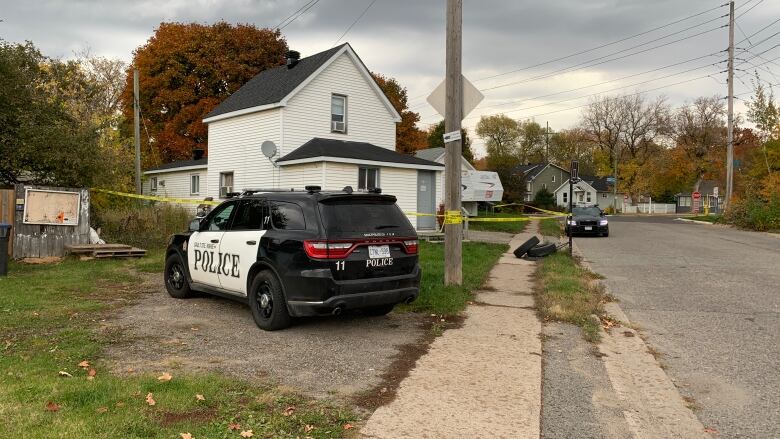 A white house with a police cruiser parked in front of it.