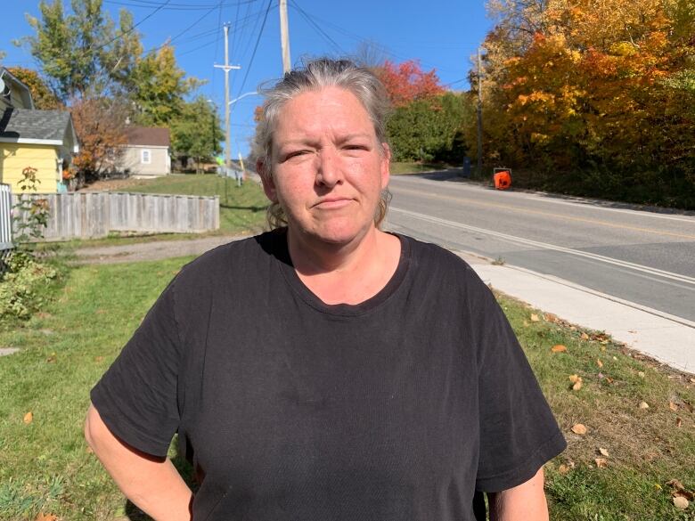 A woman standing outside, wearing a black T-shirt.