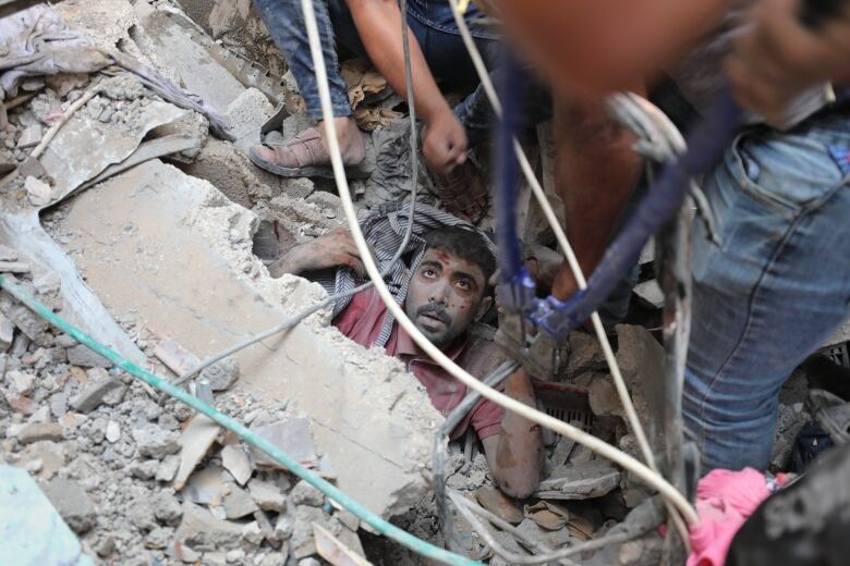 People work to rescue a person trapped under rubble.