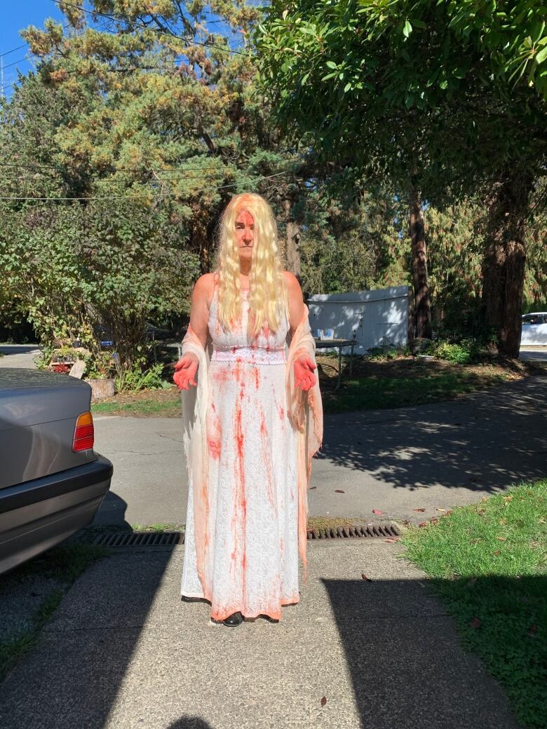 A woman dressed as a bride with red bloodstains.