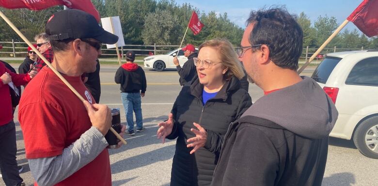 A union president talks to workers on a picket line.