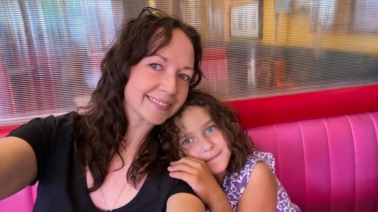 A woman is pictured sitting in a booth with her daughter. 