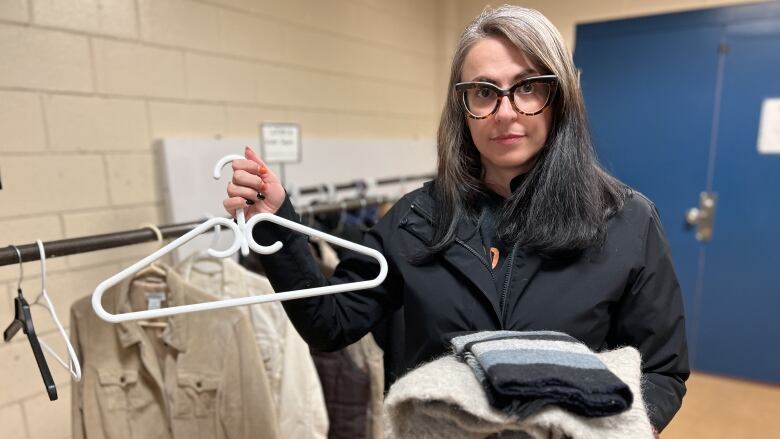 A woman a clothing hanger and glasses. 