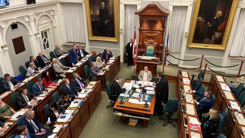 People sit at desks in a big room.