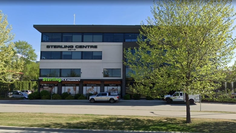 A building called Sterling Centre is photographed from across the street with a tree slightly covering the right half of the building.