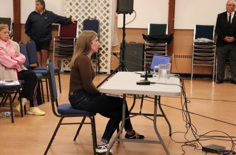 A woman sitting at a table with microphones in front of her. 