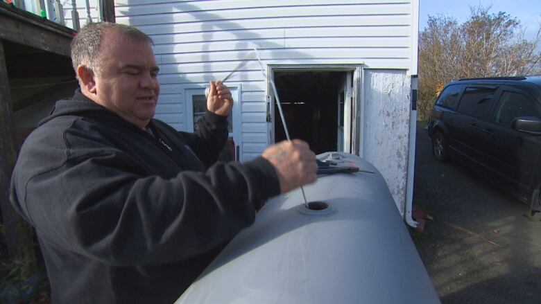 A man pulls a rod out of a oil tank.