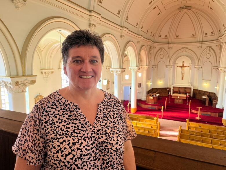 A woman in a patterned dress stands inside a church.