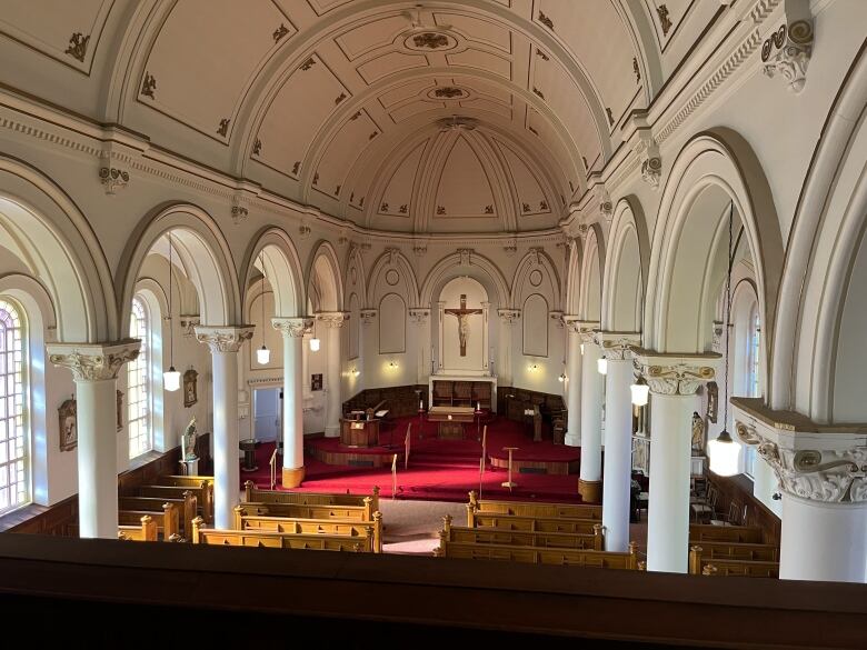 The interior of a church is seen with a curved ceiling and white Tuscan columns.