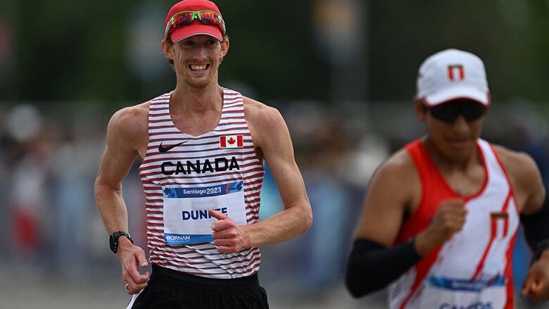 A smiling Canadian men's race walker, sporting a red ball cap, shades and a red and white striped singlet, competes in the 20 km event at the Pan American Games in Santiago, Chile.