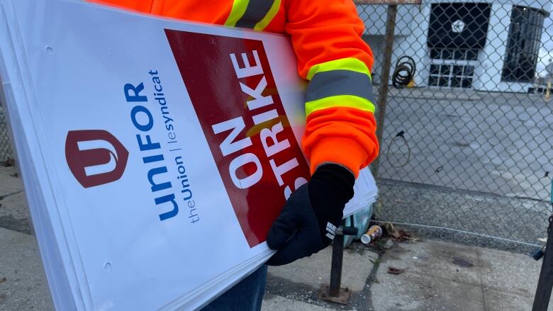 A Unifor member in Windsor, Ont., gathers strike signs after a tentative deal was reached with Stellantis.