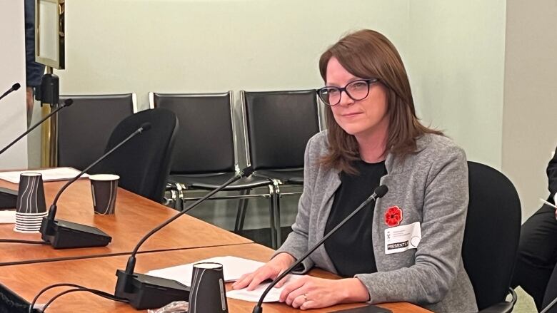 A woman with glasses sits at a table.