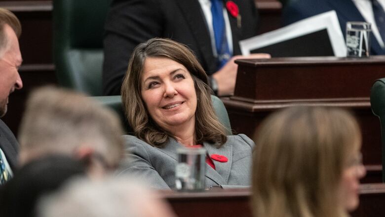 A woman sitting in the legislature smiling. 