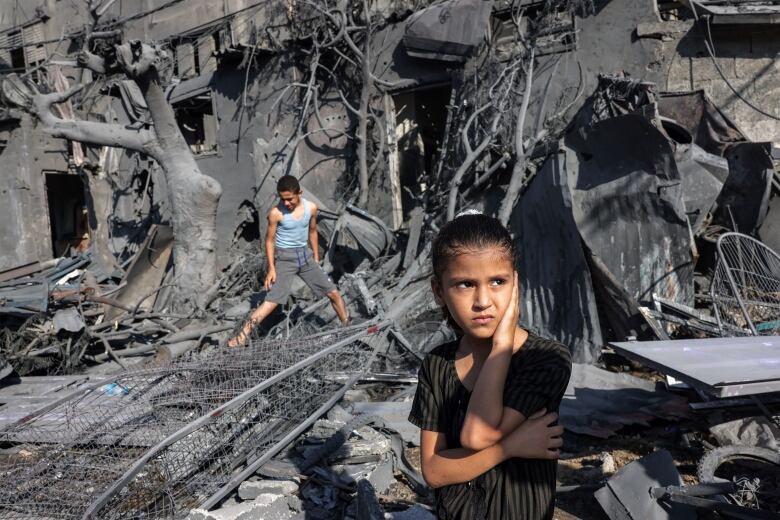 Children react while standing amid rubble.