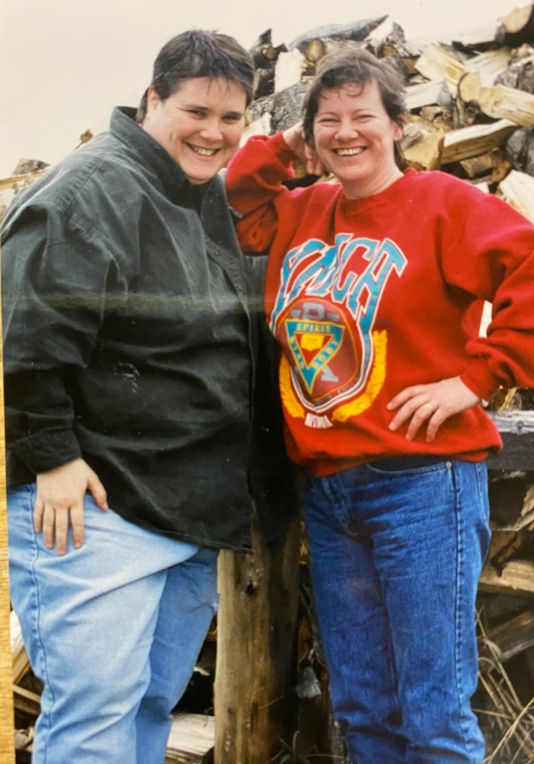 Two women stand close together smiling for the camera. 