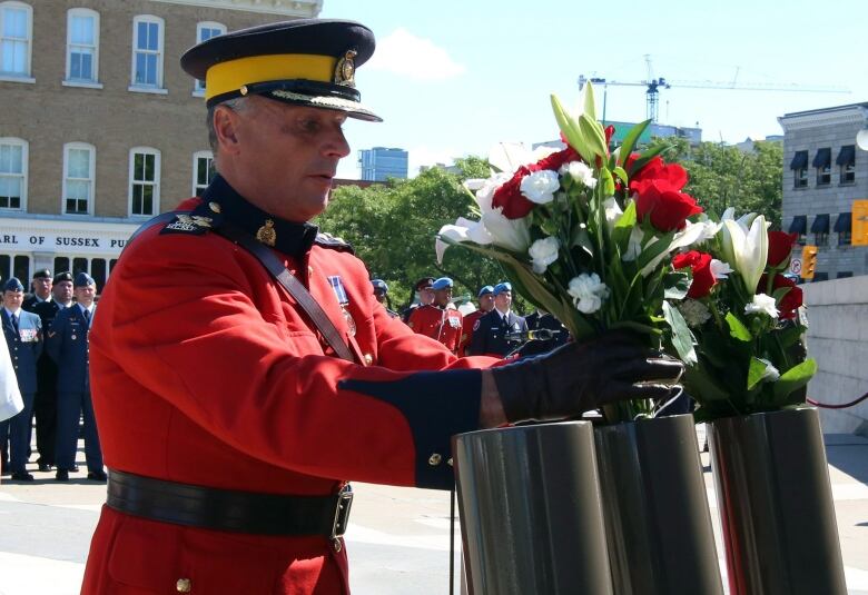 Then RCMP assistant commissioner Todd Shean places flowers in a makeshift gun barrel as he takes part in the National Peacekeepers' Day ceremony in Ottawa on Sunday, August 9, 2015. 