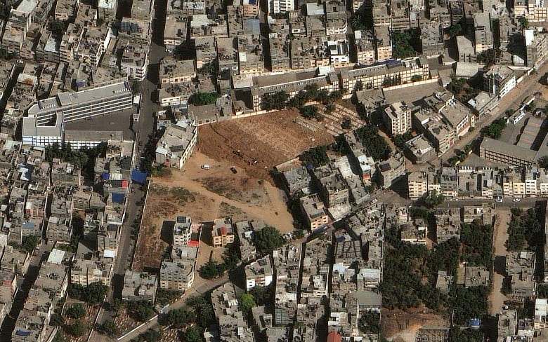 A satellite still shows an expanding cemetery with bulldozers and new graves being prepared in Gaza City.