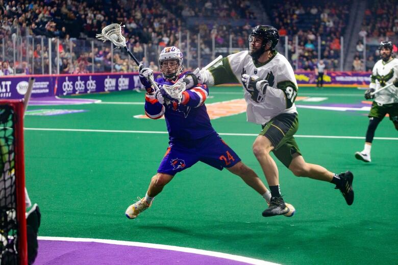 man playing lacrosse shooting a ball at a goalie