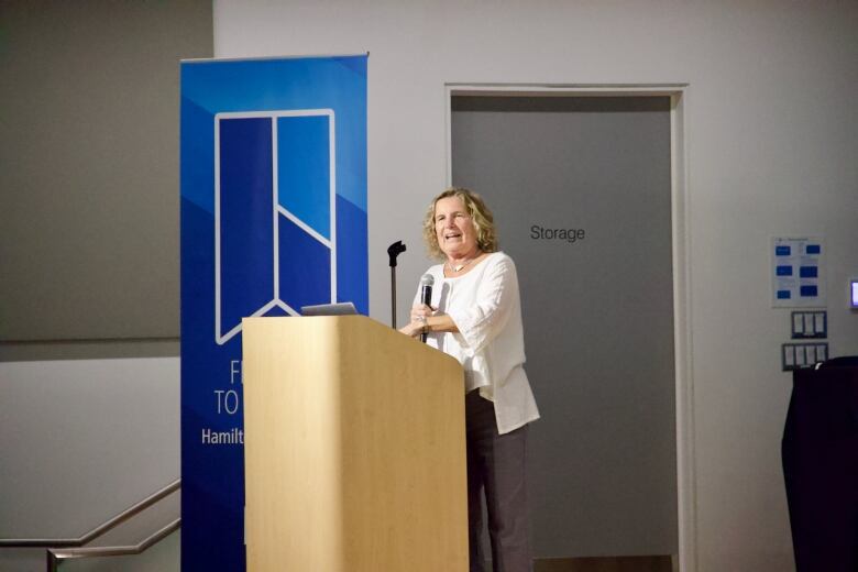 A person speaks at a microphone on a podium. 