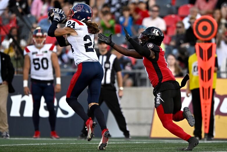 A football player in a white jersey and blue-and-red pants makes a catch.