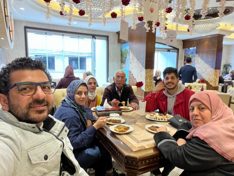 Six people sit around a table and share a meal.