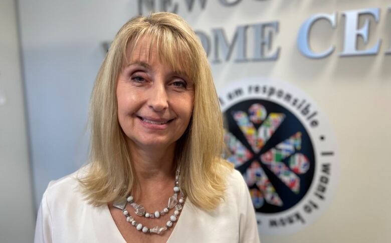 Woman with blonde hair and white shirt poses for a picture.