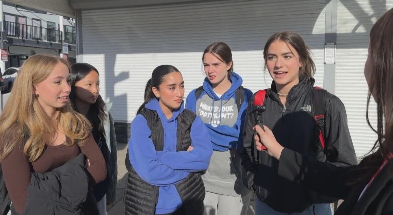 a group of five girls speak into a microphone